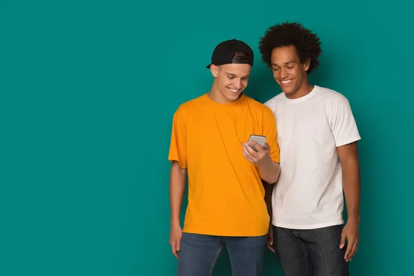Smatphone üzerinde mavi arka plan kullanarak iki genç adam — Stok fotoğraf