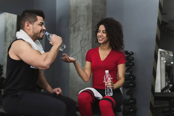 Fitness couple having rest and talking at gym