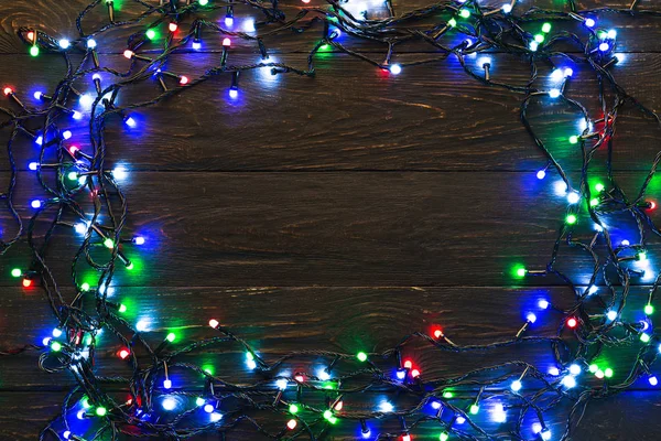 Frame of colourful garland lights on wooden background — Stock Photo, Image