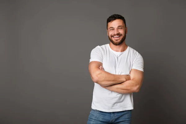 Muscoloso giovane in piedi con le braccia incrociate un — Foto Stock