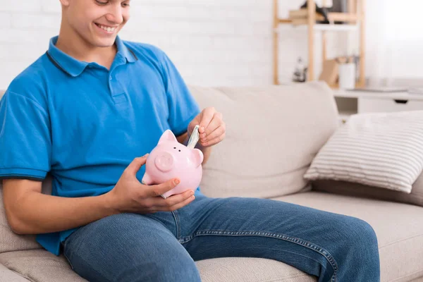 Tiener jongen geld besparen met spaarvarken — Stockfoto