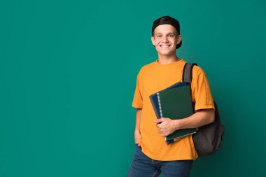 Kitap ve arka plan üzerinde sırt çantası ile genç adam