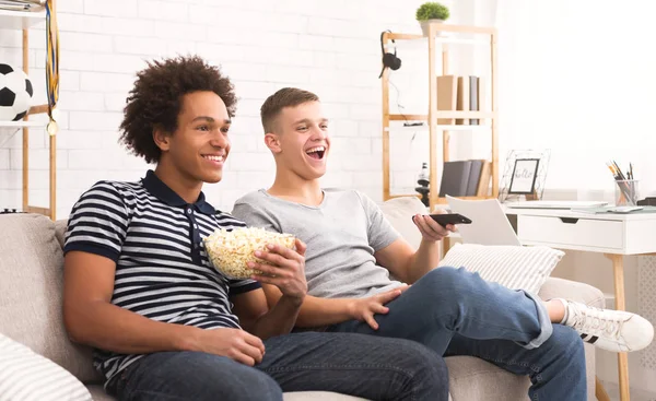 Diverse teenagers watching comedy film and eating popcorn