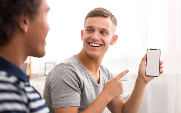 Chico feliz mostrando teléfono con aplicación a su amigo —  Fotos de Stock