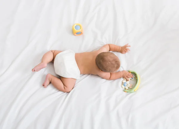 Bebê pequeno com deitado em sua barriga com brinquedos — Fotografia de Stock