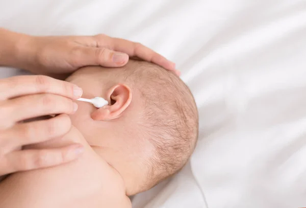 Madre limpiadora de manos oreja de bebé con hisopo de algodón —  Fotos de Stock