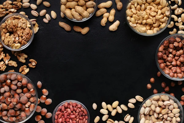 Frame of assorted nuts bowls on black background — Stock Photo, Image
