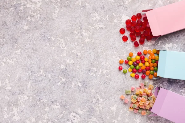 Разбрасывание разноцветных конфет из бумажных коробок на бетонном фоне — стоковое фото