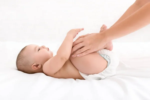 Mãe massageando seu bebê recém-nascido na cama — Fotografia de Stock