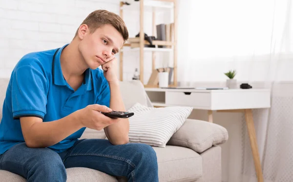 Bored teen switching channels with remote controller — Stock Photo, Image