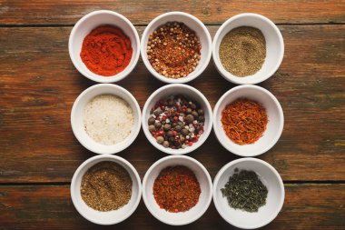 Ahşap zemin üzerine baharat ürün yelpazesine sahip. Tatlandırıcılar mutfak masasında, kopya alanı ile küçük su bardağı.