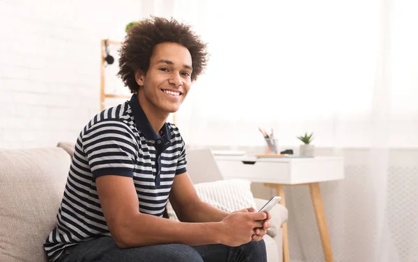 Feliz Chico Afroamericano Usando Teléfono Inteligente Mientras Está Sentado Sofá —  Fotos de Stock