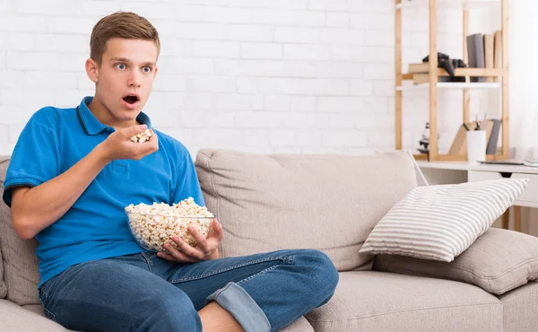 Adolescente impressionado assistindo filme e comendo pipocas — Fotografia de Stock