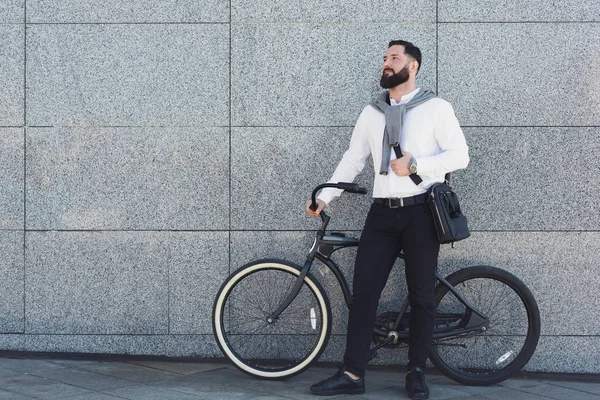 Biznesmen stojące przed budynek ściana z jego rower. — Zdjęcie stockowe