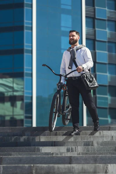 Homem de negócios barbudo carregando sua bicicleta nas escadas — Fotografia de Stock