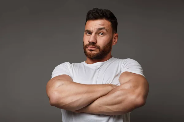 Suspicious young man with crossed big muscular arms — Stock Photo, Image