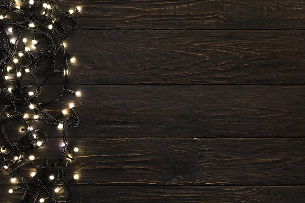 Рождественский темный деревянный фон украшен сияющими огнями — стоковое фото