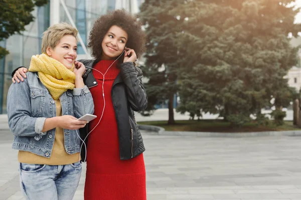 Happy female friends listen to music outdoors — Stock Photo, Image