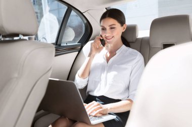 Dizüstü bilgisayar ile arabada oturan kadın girişimci