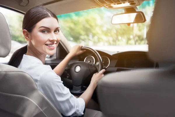 Lächelnde Geschäftsfrau sitzt im Auto und blickt in die Kamera — Stockfoto