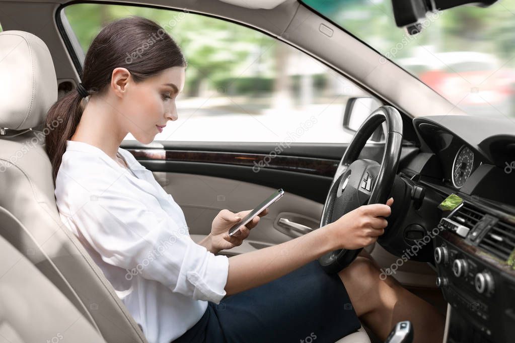 Businesswoman texting on smartphone while driving car