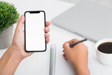 Defter üzerinde yazma ve smartphone kullanarak Fmale öğrenci el