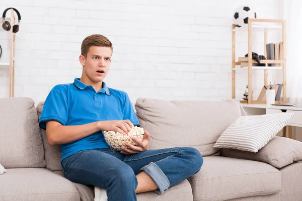 Tipo interesado viendo películas y comiendo palomitas de maíz — Foto de Stock