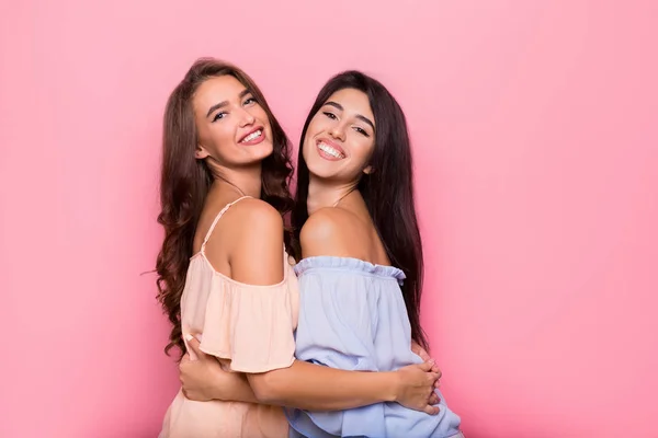 Emocionado niñas abrazando en rosa fondo del estudio — Foto de Stock