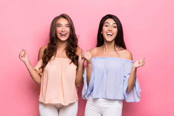 Emocionados amigos damas de pie sobre fondo rosa — Foto de Stock