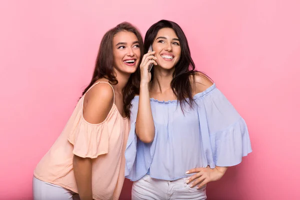 Mujeres felices disfrutando de la charla telefónica sobre fondo rosa — Foto de Stock