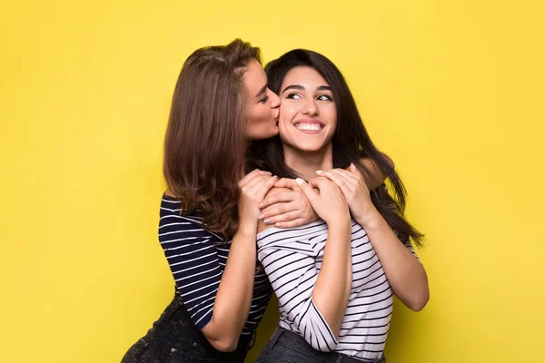 Meninas felizes abraçando no fundo do estúdio amarelo — Fotografia de Stock