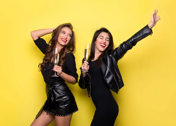 Zwei schöne Mädchen in schwarzen Jacken haben Spaß mit Champagner — Stockfoto