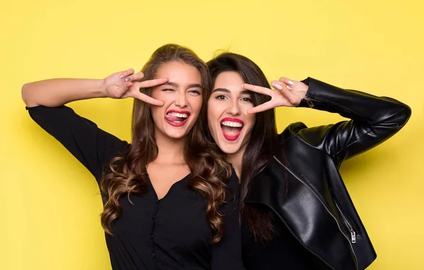 Deux filles ludiques gesticulant v-signe près des yeux sur jaune — Photo