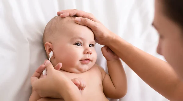 Mãe mão limpeza orelha do bebê com cotonete — Fotografia de Stock