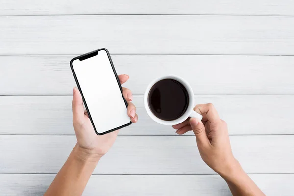 Hand mit Smartphone auf weißem Holzhintergrund — Stockfoto