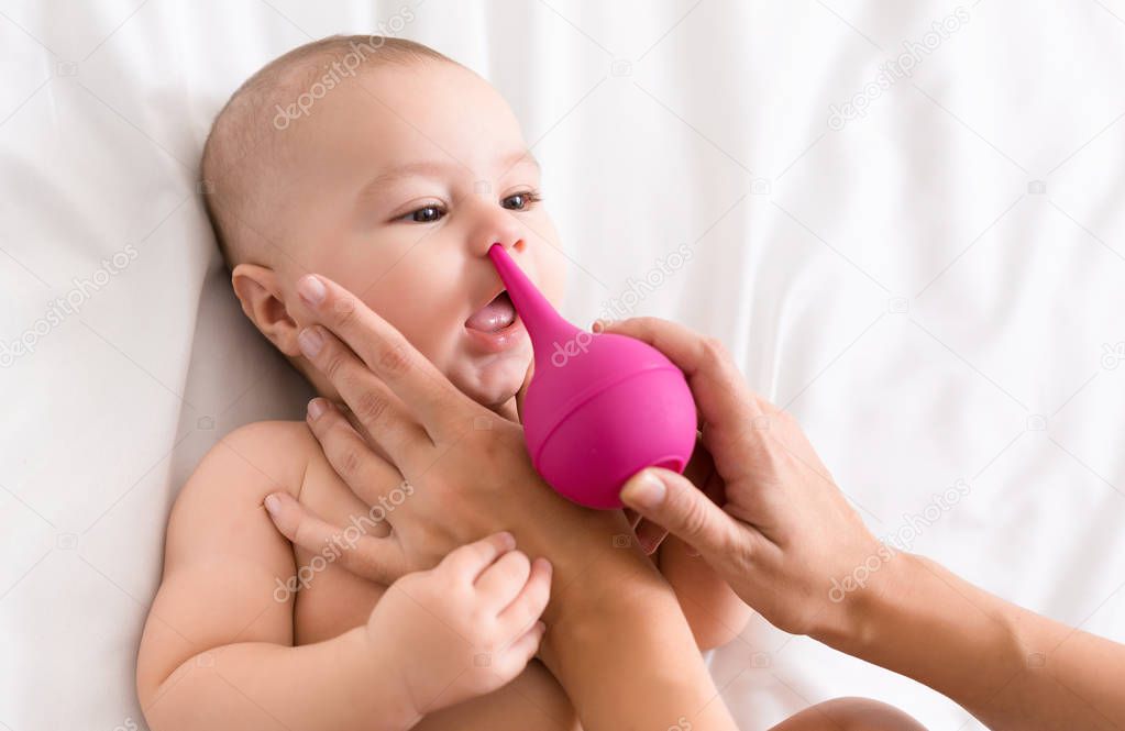 Newborn baby getting nose cleaning with cleaner