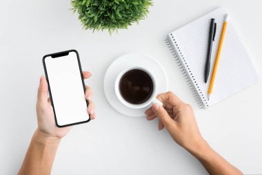 Cep telefonu ve kahve fincanı tutan kadın