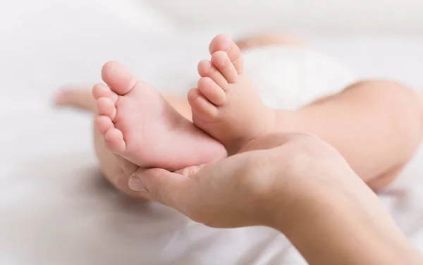 Pequeño bebé pies en madre manos primer plano — Foto de Stock