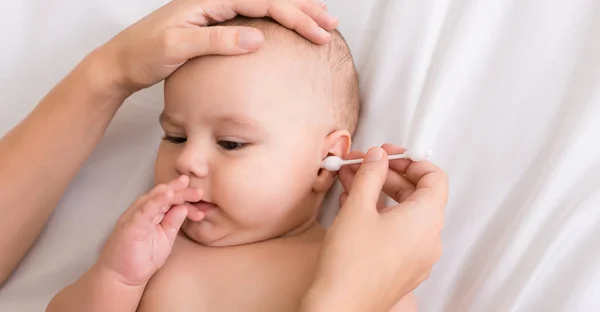 Мати очищає дитяче вухо з ватним тампоном — стокове фото