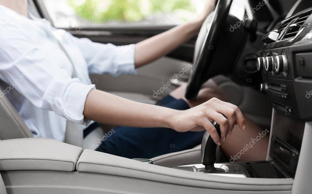 Businesswoman driving car and shifting automatic transmission