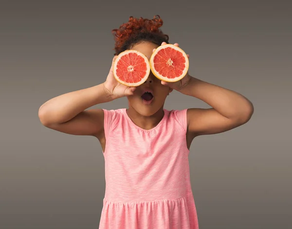 Lilla afroamerikansk flicka som leker med färska citrusfrukter — Stockfoto