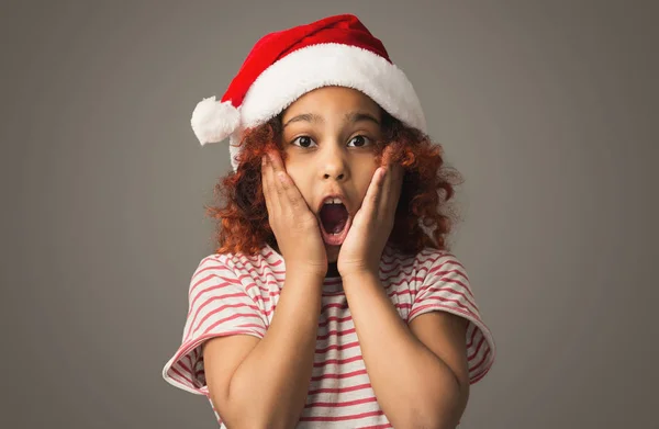 Malé afro dívka v santa hat na šedé studio pozadí — Stock fotografie