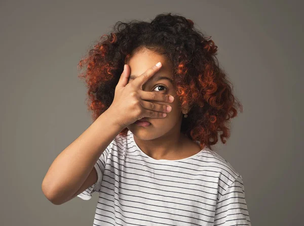 Afro capretto ragazza peeking anche se dita su sfondo grigio — Foto Stock