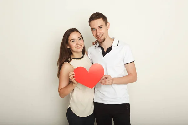 Joven feliz pareja enamorada sosteniendo el corazón de papel rojo — Foto de Stock