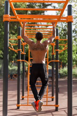 Gönderme yapan Afrikalı-Amerikalı kaslı erkek ups üzerinde yatay çubuk