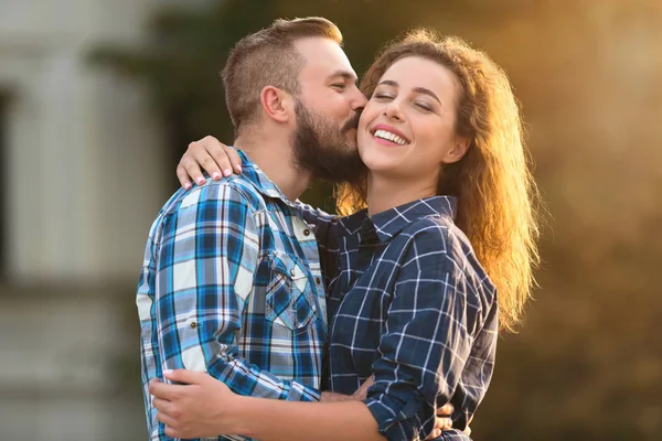 Красивый мужчина нежно целует свою девушку в щеку на улице — стоковое фото