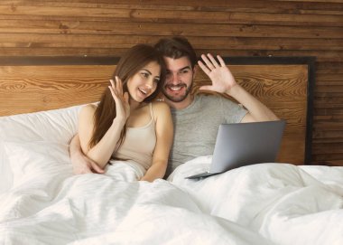 Çift yatakta dizüstü bilgisayarda görüntülü arama yapma