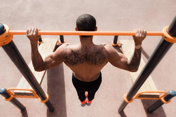 Tatuado homem fazendo pull up exercício, vista superior — Fotografia de Stock