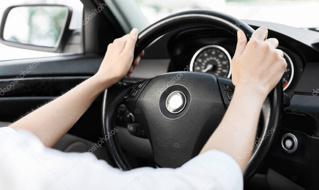 Woman driving car with hands on steering wheel