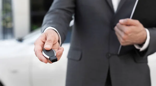 Mann im Anzug gibt Autoschlüssel nach Unterzeichnung des Autokaufs ab — Stockfoto